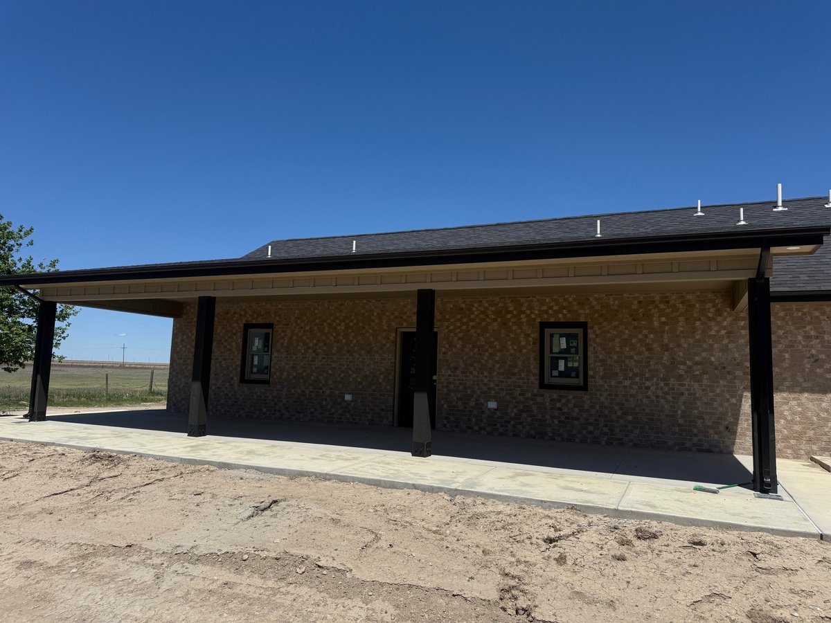 Modern brick building with black metal awning and support beams under clear blue sky