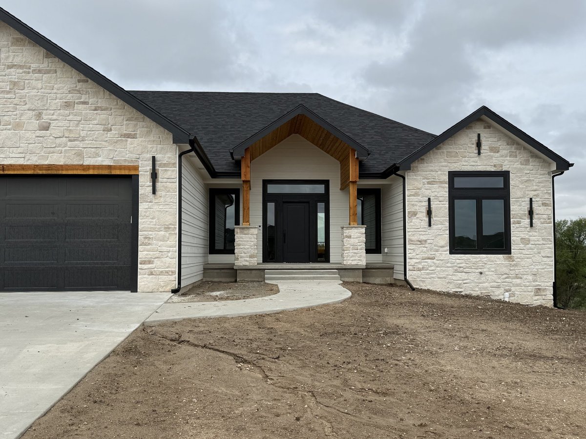 Modern white brick single-story house with black roof, dark trim, wooden arch over entrance, and attached dark gray garage